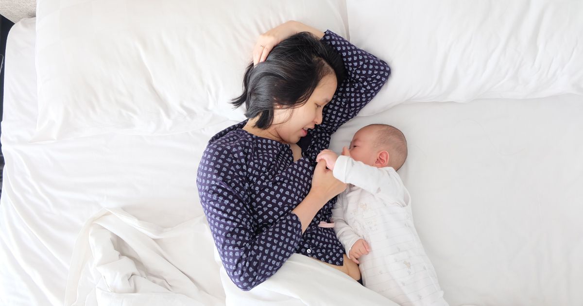 mom breastfeeding baby in bed