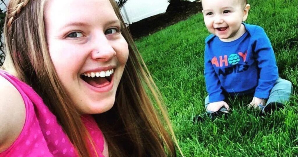 new mom smiling outdoors with baby