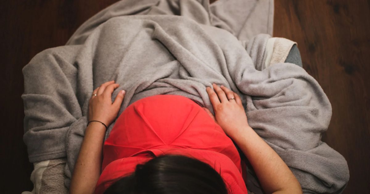 pregnant woman in red shirt under blanket
