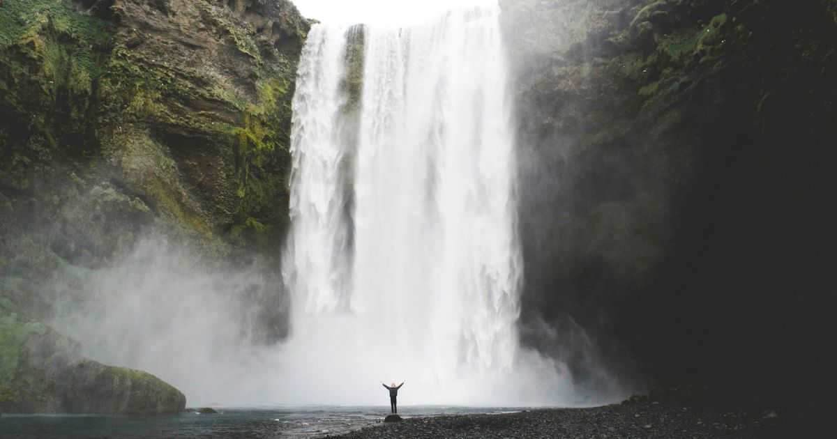 woman standing at edge of waterfall
