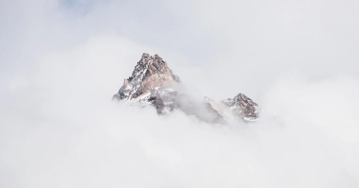 snow covered mountain peak in clouds