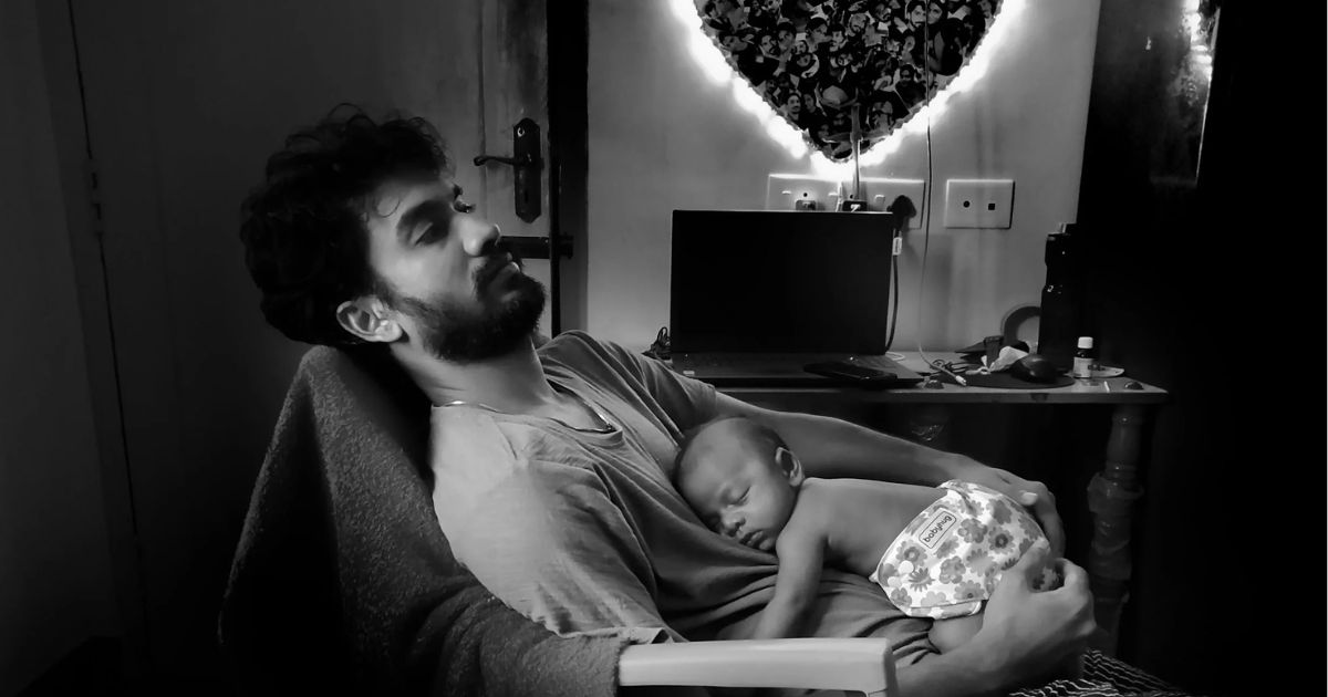 new dad sleeping with baby on his lap in chair