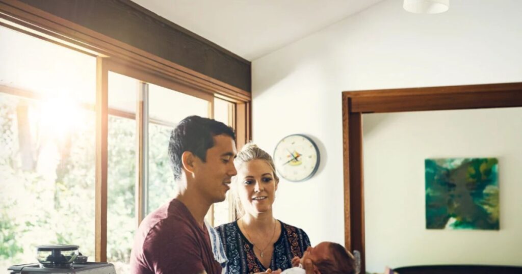 new dad holding baby with doula by his side