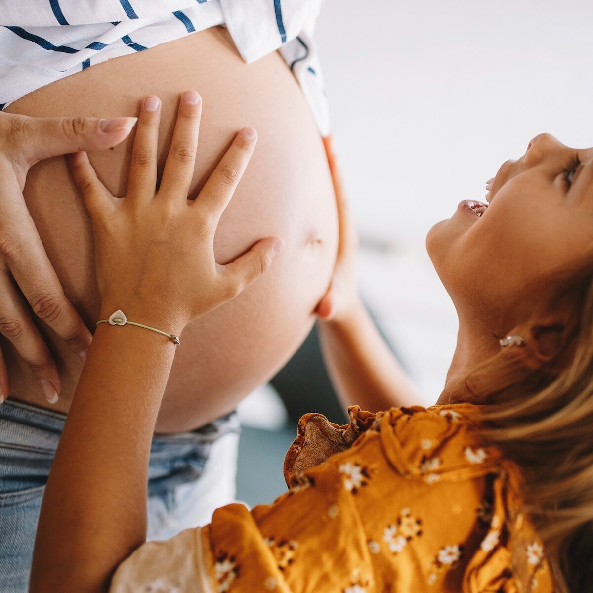 happy older sibling touching mom's pregnant belly